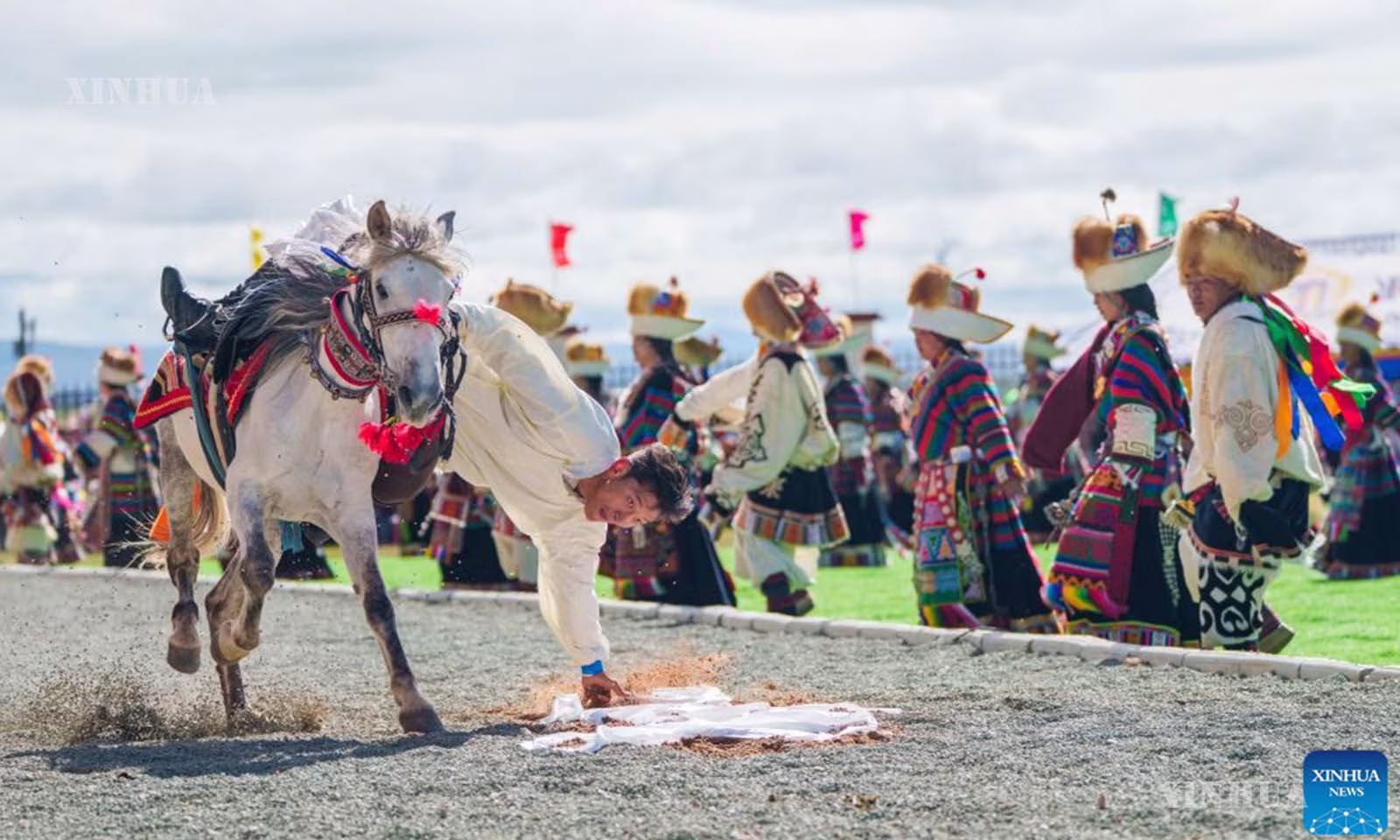 တရုတ်နိုင်ငံ အနောက်တောင်ပိုင်း ရှီးဇန့် ကိုယ်ပိုင်အုပ်ချုပ်ခွင့်ရဒေသ အန်းသော ခရိုင်တွင် မြင်းစီးပြိုင်ပွဲ ဖွင့်ပွဲအခမ်းအနား၌ မြင်းကျောကုန်းပေါ်မှ ရှီးဇန့် ရိုးရာ လည်စည်းပိုးပဝါ hada ကို ကောက်ယူကာ မြင်းစီးစွမ်းရည်ပြသနေသည့် မြင်းစီးသမားတစ်ဦးကို ၂၀၂၆ ခုနှစ် ဇူလိုင် ၂၃ ရက်က တွေ့ရစဉ် (ဆင်ဟွာ)